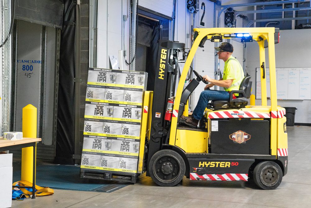 A man driving a yellow forklift in a warehouse.